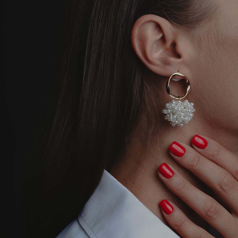 Cercei magnetici purtati de o fata cu unghii rosii si camasa cu guler alb